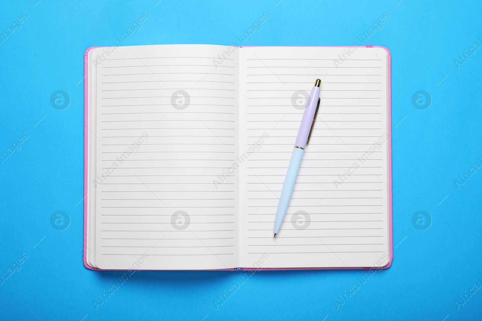 Photo of Open notebook and pen on light blue background, top view