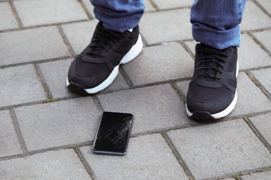 Man near dropped smartphone on pavement, closeup. Device repairing