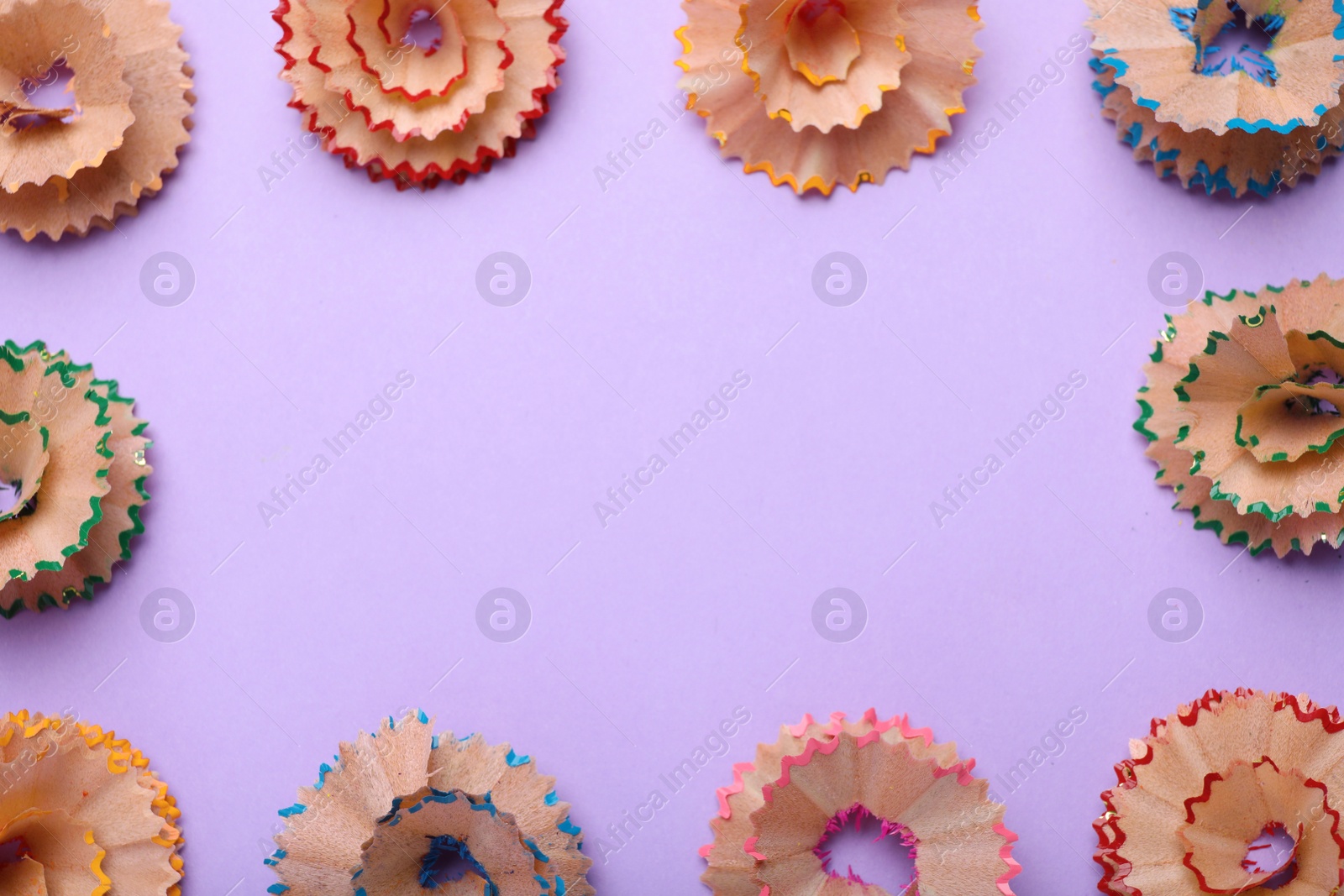 Photo of Colorful wooden pencil shavings on violet background, flat lay. Space for text