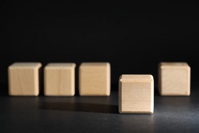 Photo of Empty wooden cubes on grey table against black background