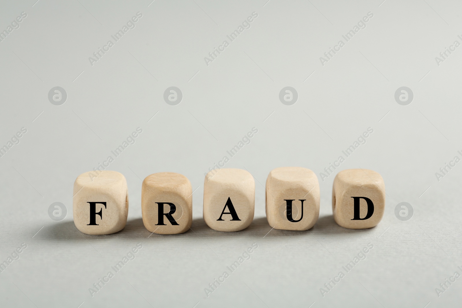 Photo of Word Fraud of wooden cubes with letters on light grey background. Space for text