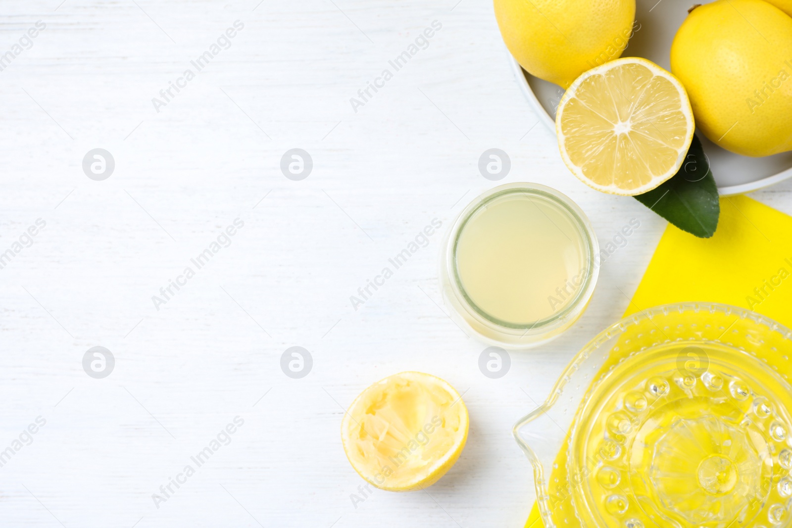 Photo of Flat lay composition with freshly squeezed lemon juice on white wooden table. Space for text