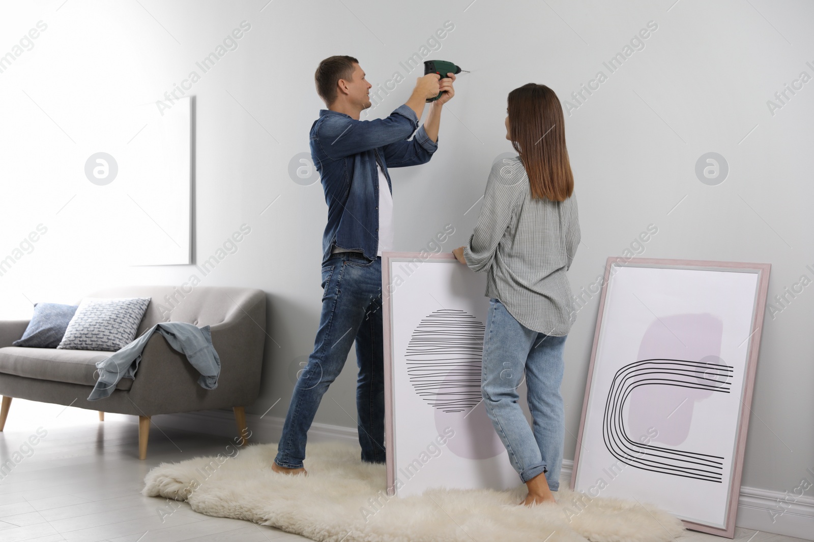 Photo of Couple decorating room with pictures together. Interior design
