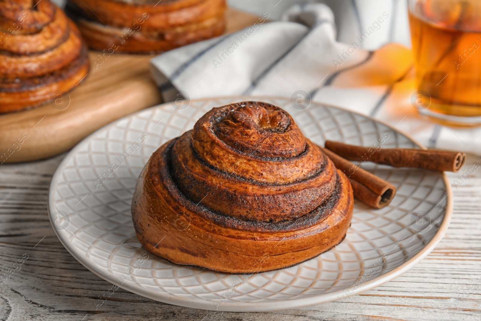 Photo of Plate with cinnamon roll on wooden table