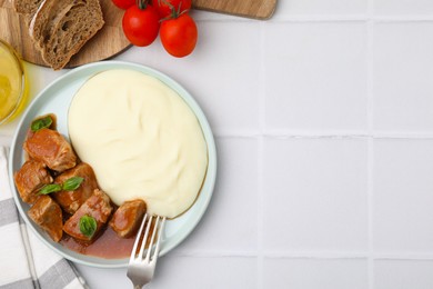 Photo of Delicious goulash served with mashed potato on white tiled table, flat lay. Space for text