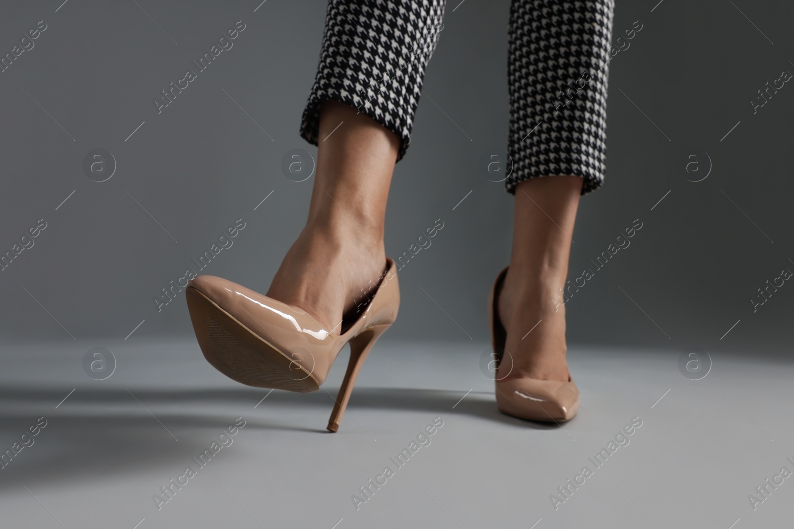 Photo of Businesswoman in beige shoes on grey background, closeup