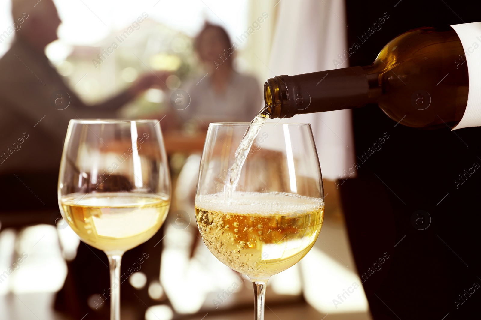 Photo of Waitress pouring wine into glass in restaurant, closeup