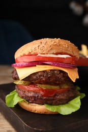 Photo of Tasty cheeseburger with patties on wooden table, closeup