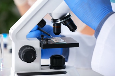 Photo of Scientist working with microscope in laboratory, closeup. Research and analysis