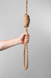 Photo of Man holding rope noose on light background, closeup