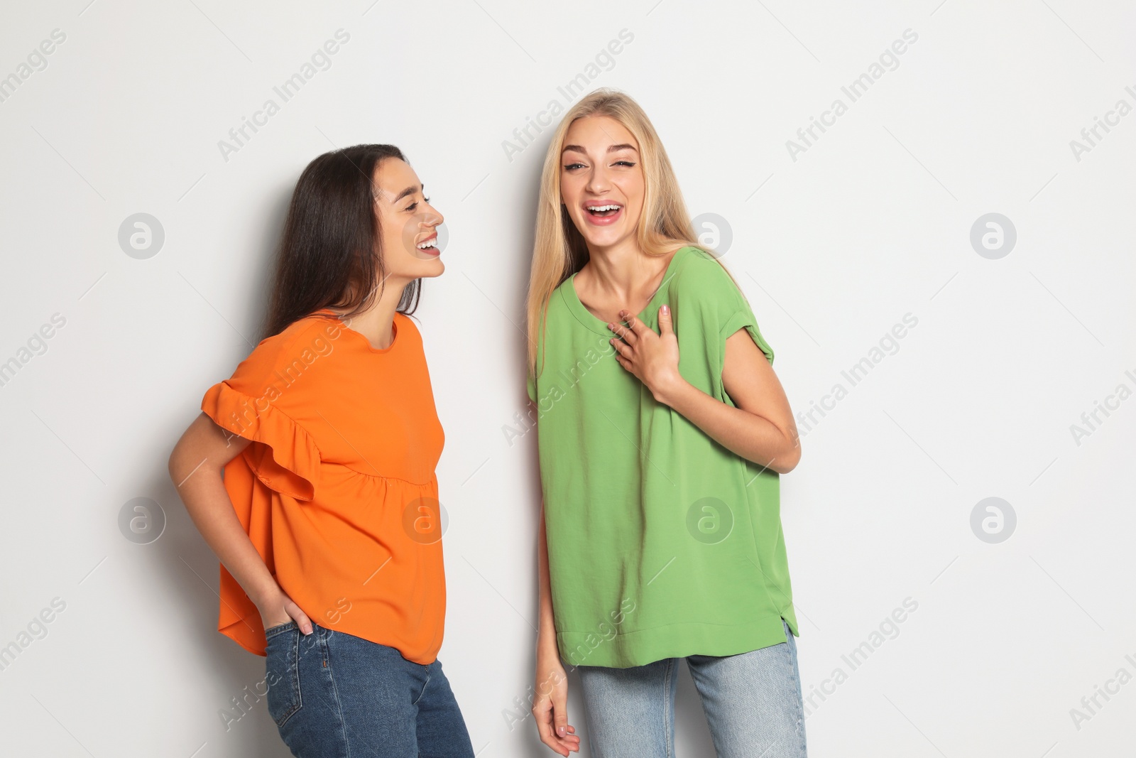 Photo of Young women laughing together against light background