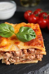 Photo of Delicious cooked lasagna served on slate plate, closeup