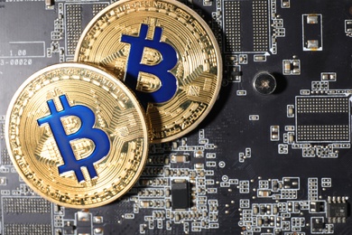 Photo of Golden bitcoins on computer circuit board, top view. Space for text