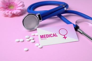 Stethoscope, business card with pills and flower on color background. Gynecological care