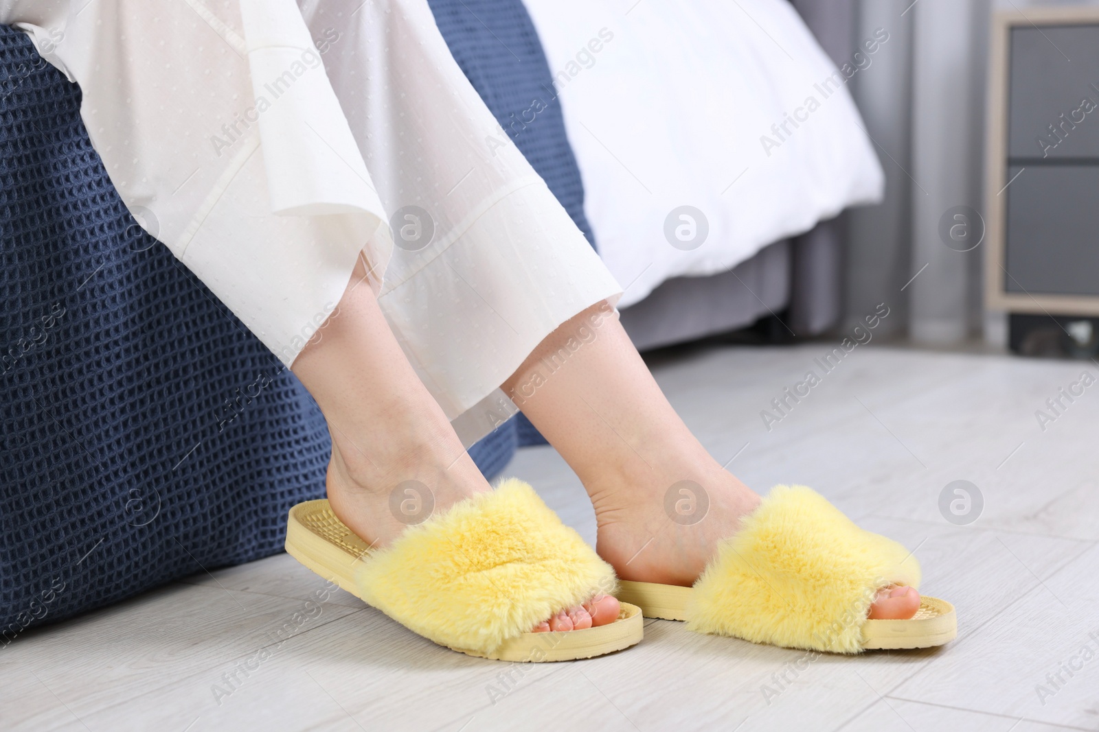 Photo of Woman in yellow soft slippers at home, closeup