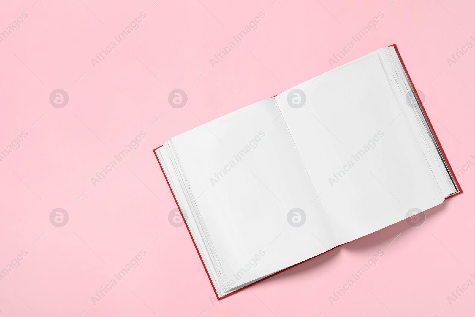 Photo of Open book with blank pages on pink background, top view. Space for text