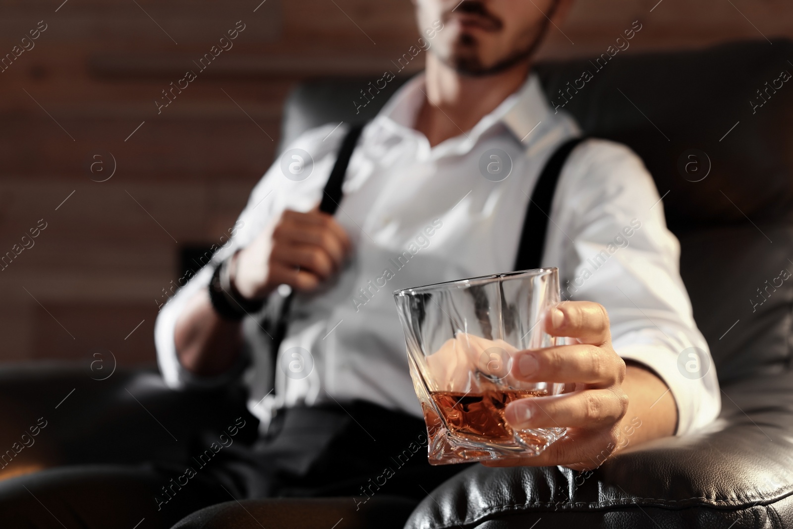 Photo of Man with glass of whiskey sitting in armchair, closeup. Space for text