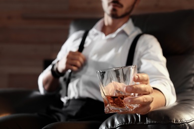 Photo of Man with glass of whiskey sitting in armchair, closeup. Space for text