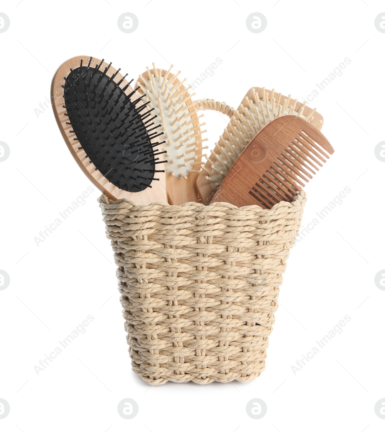 Photo of Different wooden hair brushes in wicker holder isolated on white