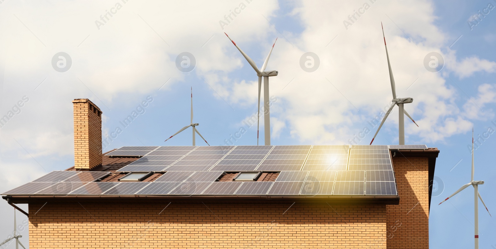 Image of Wind turbines near house with installed solar panels on roof. Alternative energy source