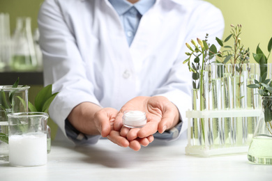 Photo of Woman holding cream at table in cosmetic laboratory, closeup