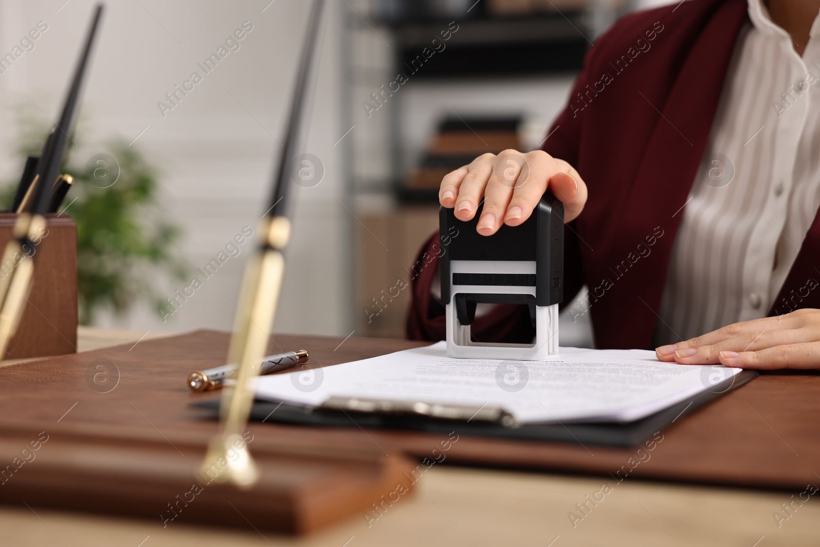 Photo of Notary stamping document at table in office, closeup