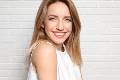 Portrait of young woman with beautiful face near white brick wall