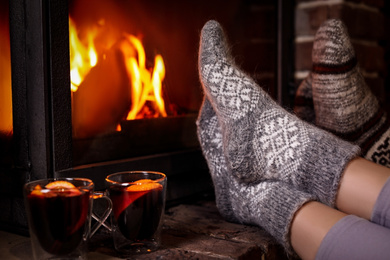 Photo of People with mulled wine resting near fireplace indoors, closeup