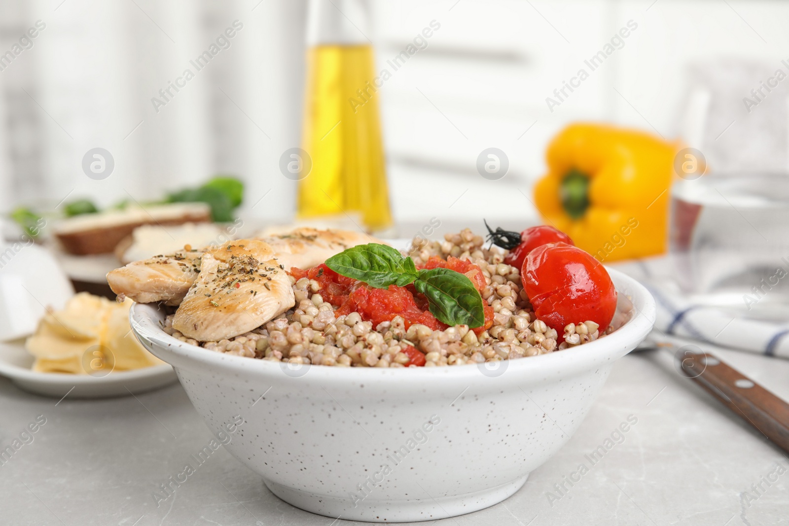 Photo of Tasty buckwheat porridge with meat and vegetables on grey marble table