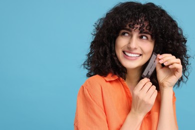 Young woman holding teeth whitening strips on light blue background, space for text