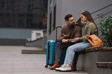Being late. Worried couple sitting on bench outdoors, space for text