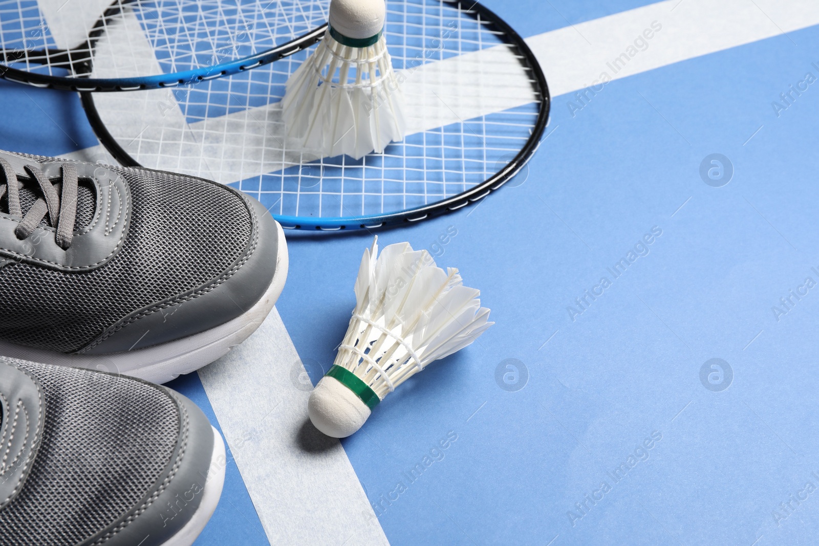 Photo of Feather badminton shuttlecocks, rackets and sneakers on court, space for text