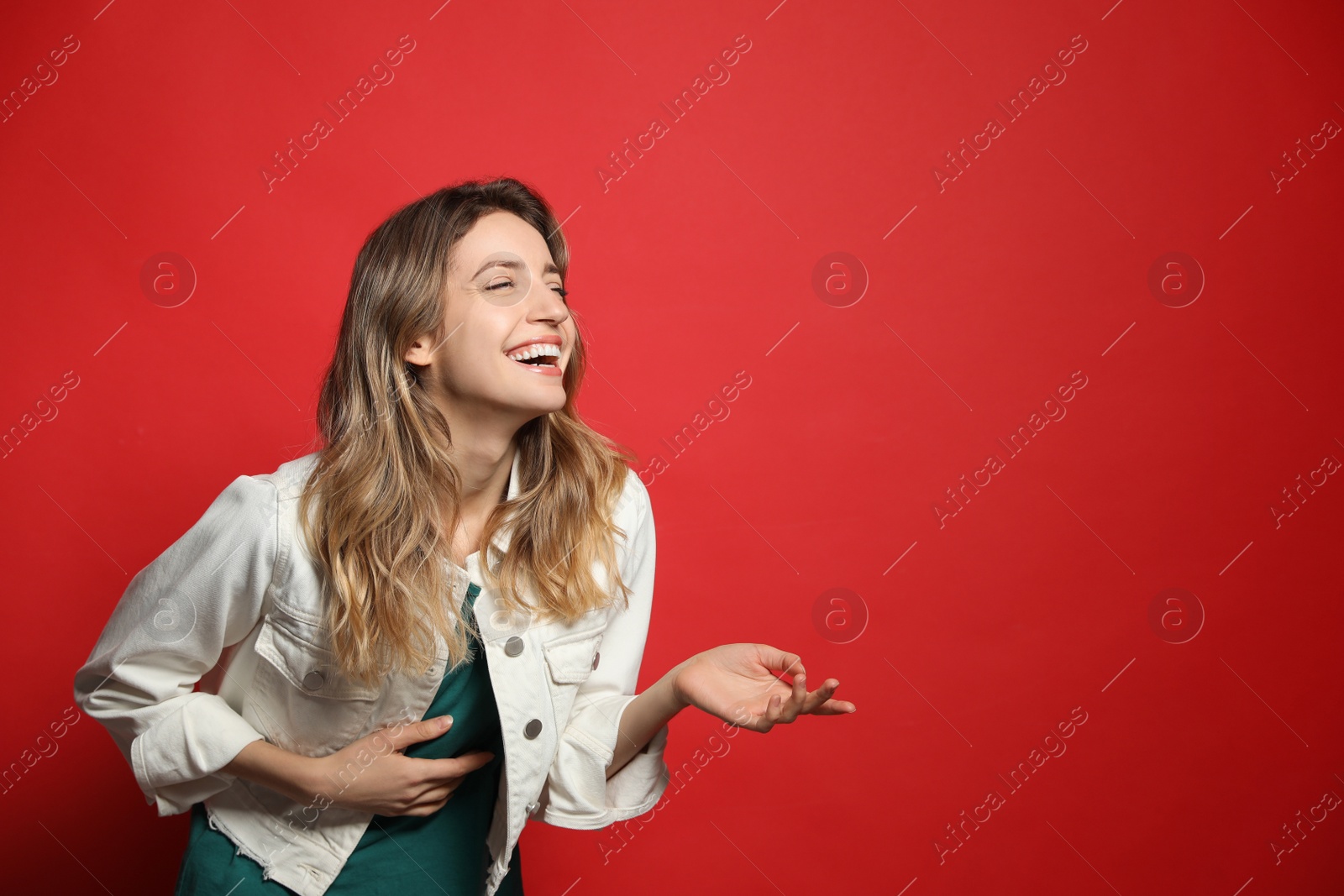 Photo of Cheerful young woman laughing on red background. Space for text