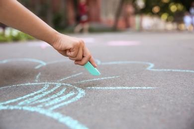 Little child drawing with chalk on asphalt, closeup