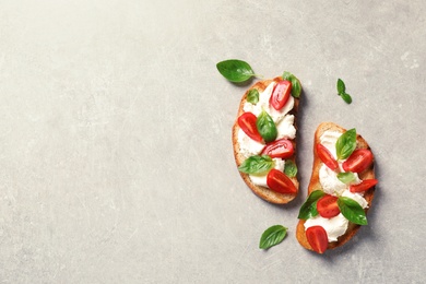 Photo of Toasted bread with tasty cream cheese and tomatoes on gray background, flat lay. Space for text