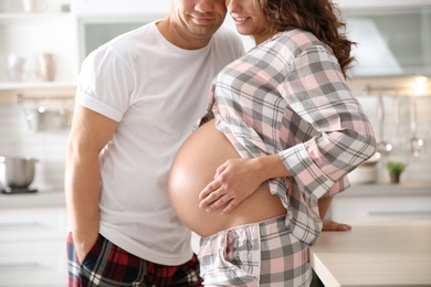 Pregnant woman with her husband in kitchen. Happy young family