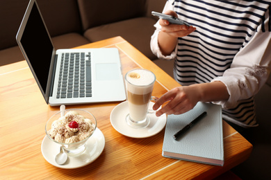 Photo of Blogger taking picture of dessert and coffee at table in office