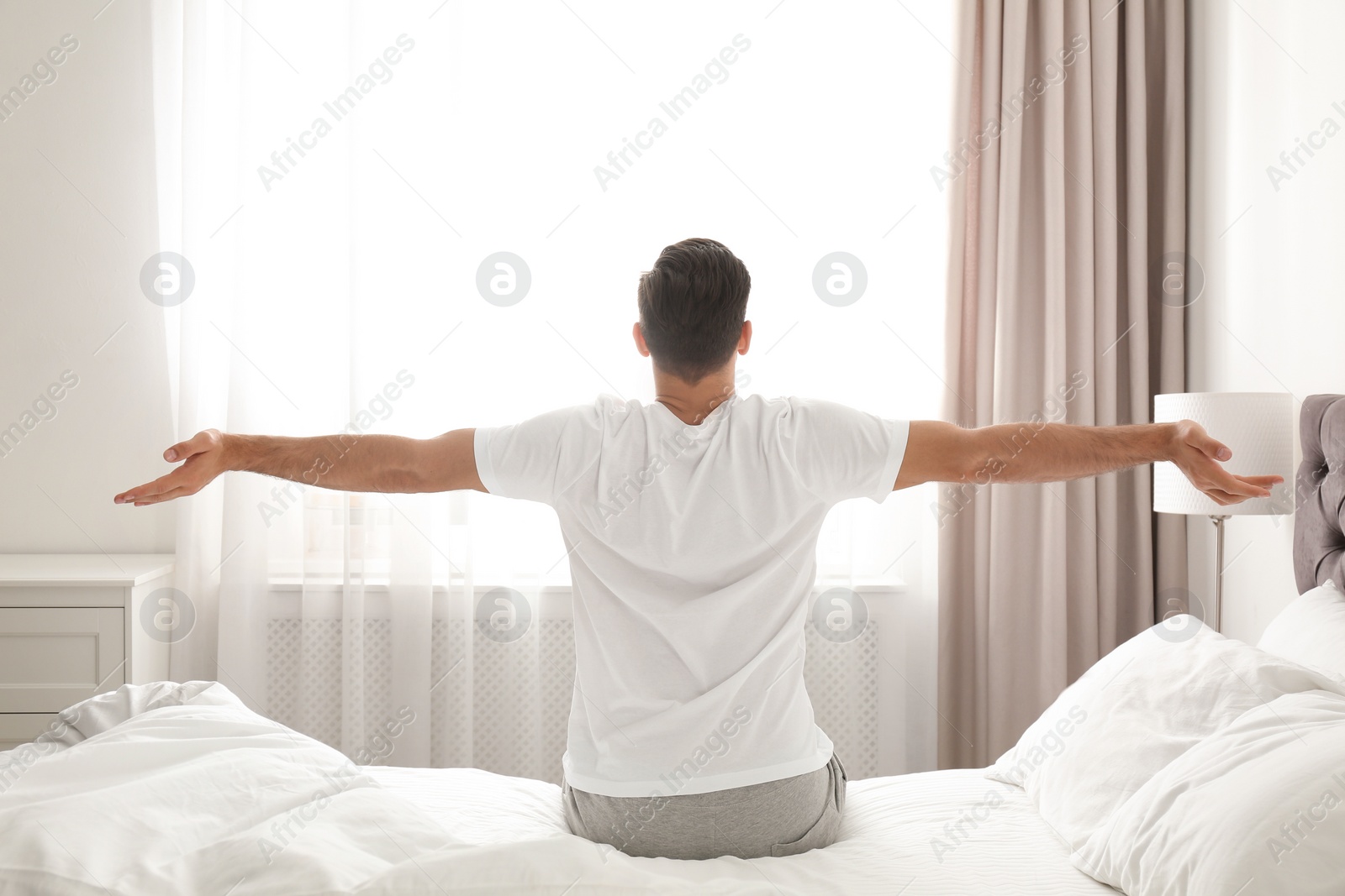 Photo of Man awakening on bed at home. Lazy morning