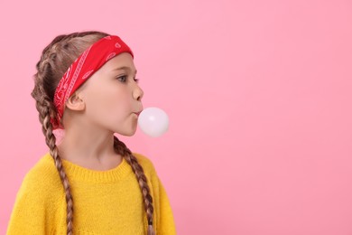 Photo of Girl blowing bubble gum on pink background, space for text