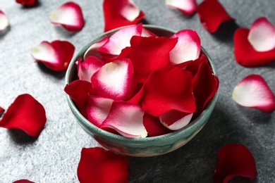 Photo of Bowl with rose petals on grey background