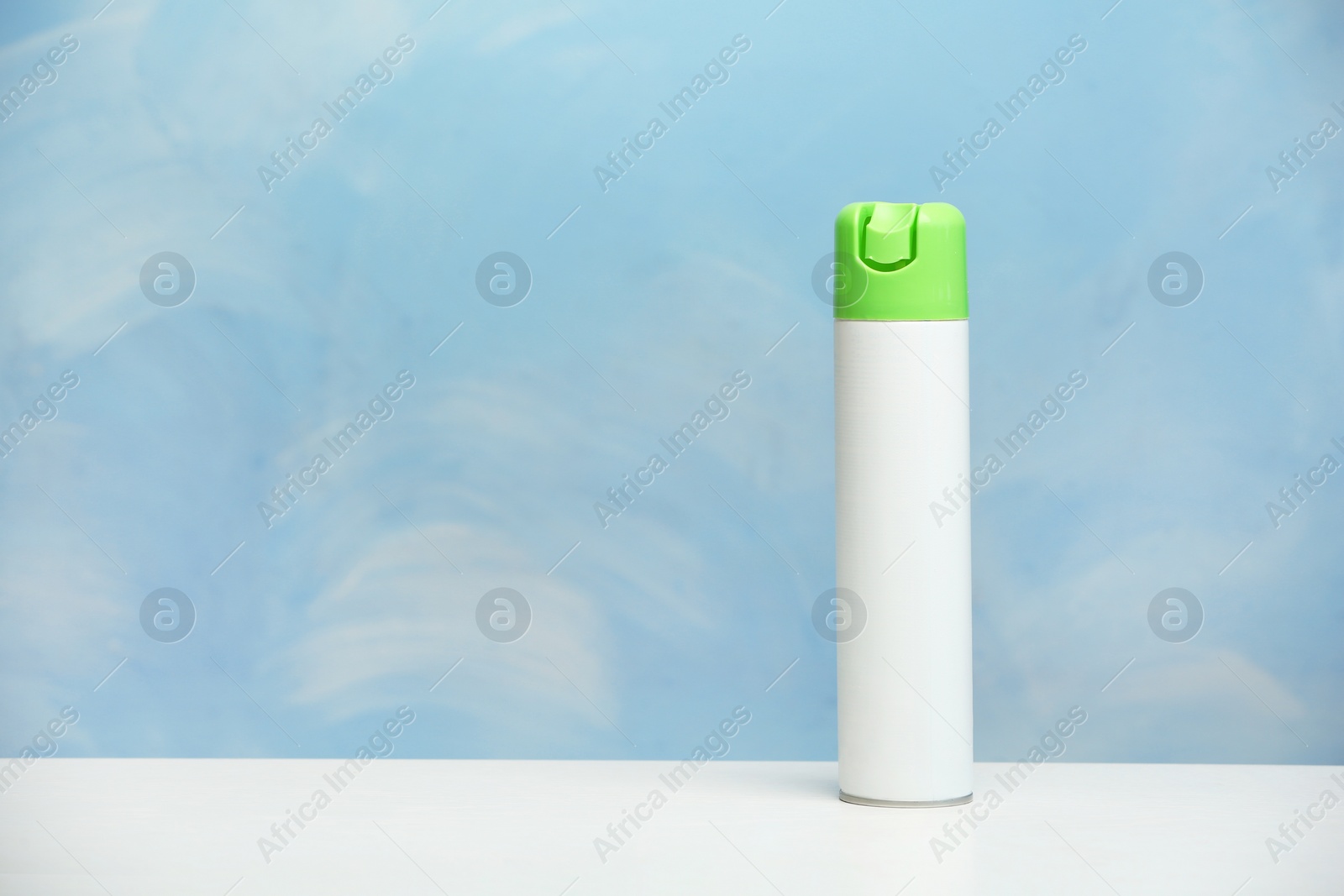 Photo of Spray air freshener on table against color background