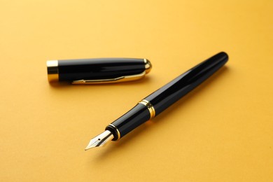 Photo of Stylish fountain pen with cap on yellow background