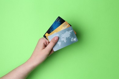 Photo of Woman holding credit cards on light green background, closeup