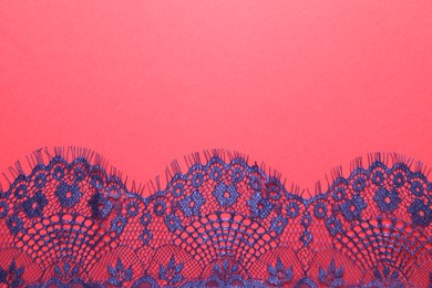 Photo of Blue lace on red background, top view. Space for text