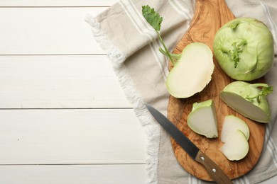 Photo of Whole and cut kohlrabi plants on white wooden table, flat lay. Space for text
