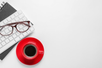 Red cup with aromatic coffee, glasses, keyboard and notepad on white background, flat lay. Space for text
