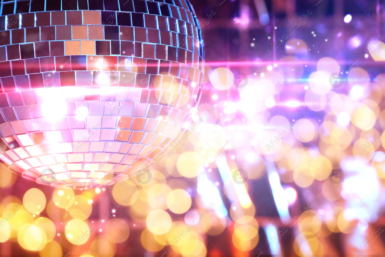 Image of Shiny disco ball on bright background with blurred lights, bokeh effect