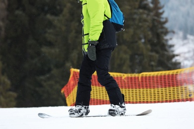 Photo of Snowboarder on slope at resort, closeup. Winter vacation