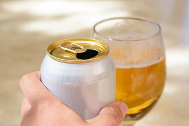 Photo of Man holding can near glass with beer at table, closeup