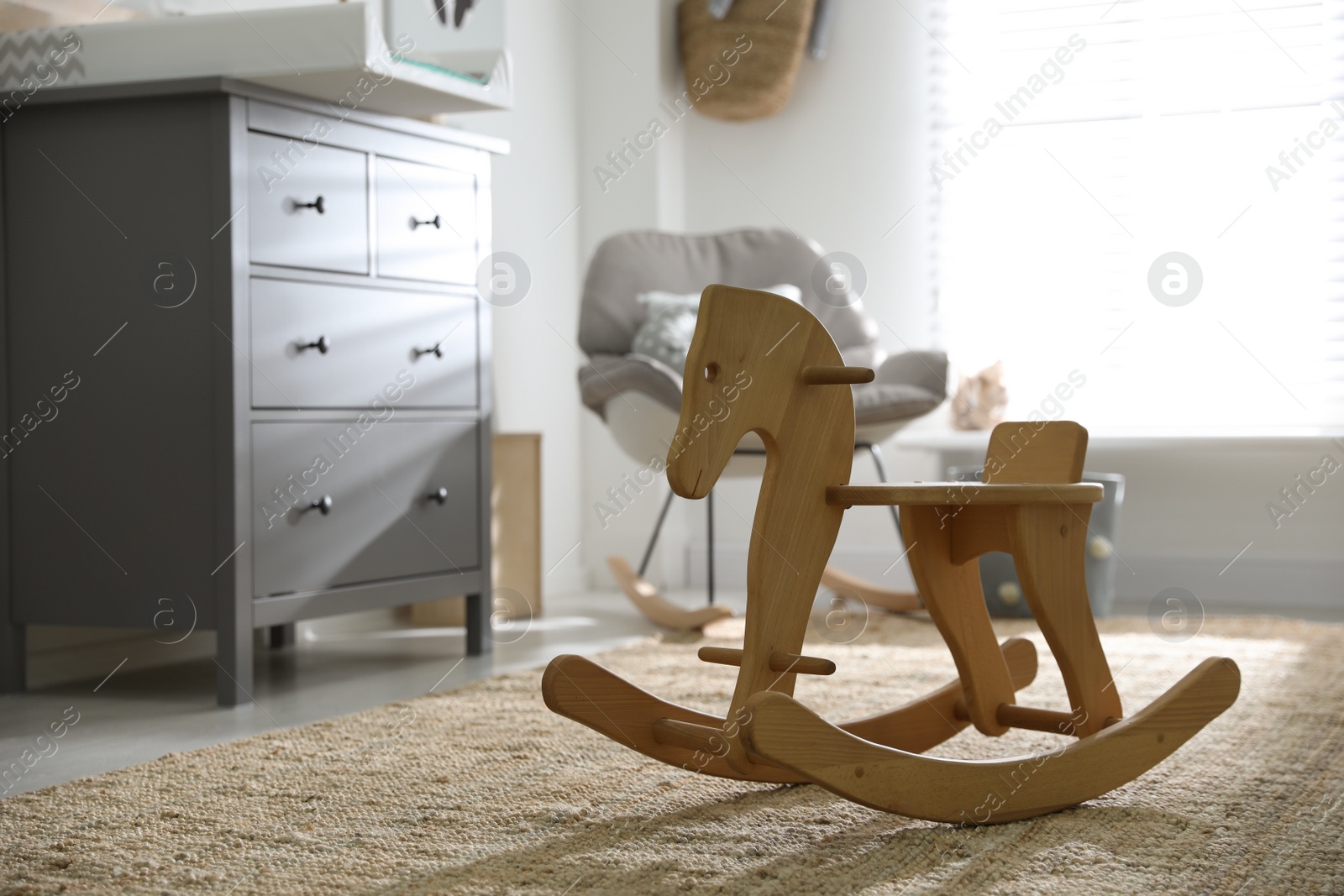 Photo of Cute wooden rocking horse in baby room interior